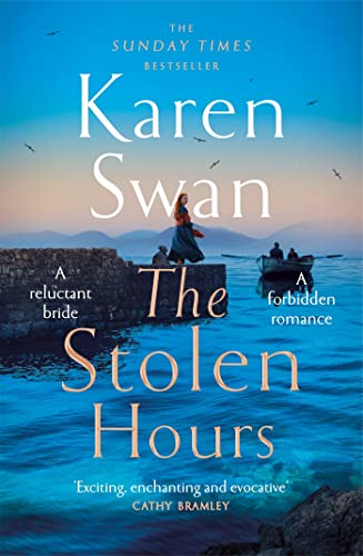 Front cover image of Karen Swan's The Stolen Hours of a young woman with red hair standing on a pier watching a boat with oars rowing toward her.